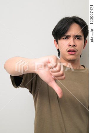 Portrait of handsome Young Asian Thai man giving thumbs down gesture against white background 133007471