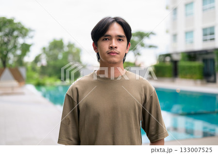 Portrait of handsome Young Asian Thai man outdoors next to swimming pool during summer 133007525