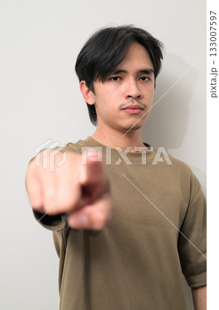 Portrait of handsome Young Asian Thai man pointing finger at camera against white background 133007597