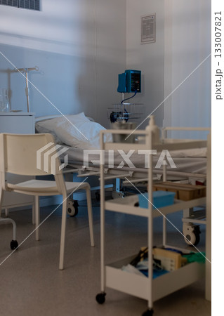 A clean and organized hospital room that features a bed along with necessary medical equipment A clean and organized hospital room that features a bed along with necessary medical equipment 133007821