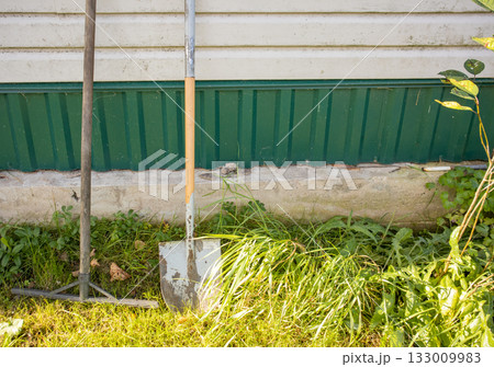 Garden tools by green house wall sunny country yard 133009983