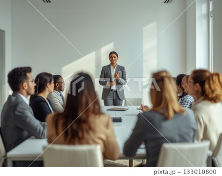 ミニマルな白いオフィスで打ち合わせをする多国籍ビジネスチーム ミニマルな白いオフィスで打ち合わせをする多国籍ビジネスチーム 133010800