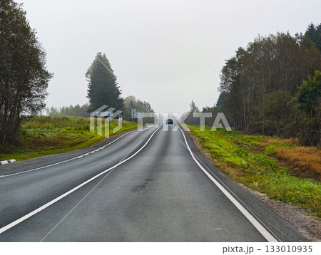 Empty rural road with a single car among greenery autumn day horizontal frame 133010935