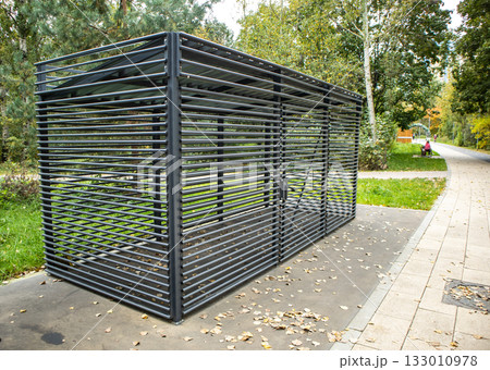 Louvered metal enclosure in city park, modern shelter with slats, horizontal frame 133010978