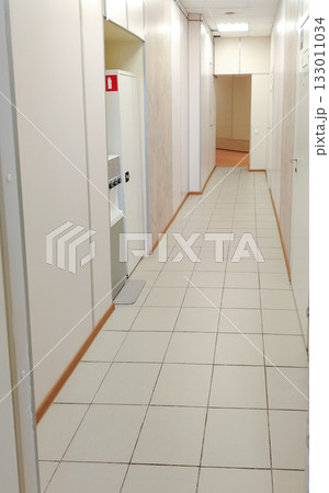 Bright office or clinic hallway with white doors and tiled floor Bright office or clinic hallway with white doors and tiled floor 133011034
