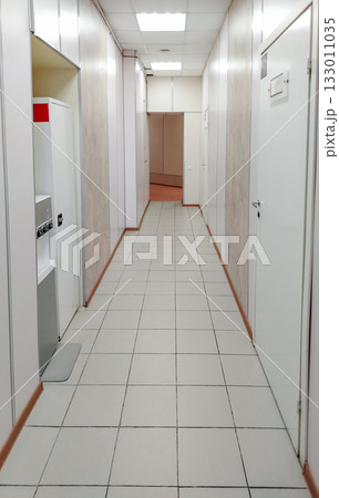 Bright office or clinic hallway with white doors and tiled floor Bright office or clinic hallway with white doors and tiled floor 133011035