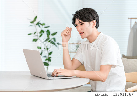 家のリビングでノートパソコンを使う若いアジア人男性（投資,ショック,トラブル,下落,リスク） 133011367