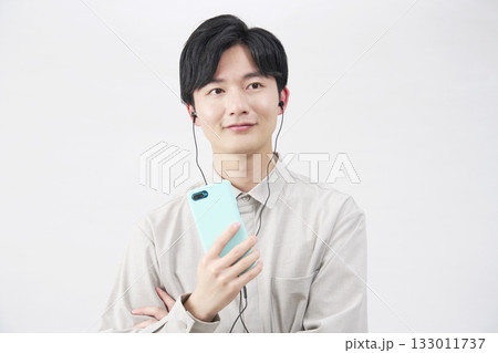 イヤホンをつけて音楽を聴く20代男性　白背景 133011737