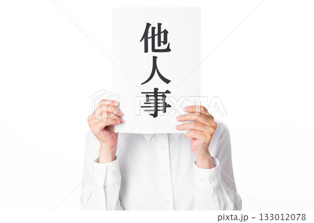 他人事と書かれた紙を両手で持つ白いシャツを着た人物 他人事と書かれた紙を両手で持つ白いシャツを着た人物 133012078