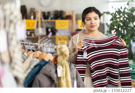 Latin woman choosing sweaters in a clothing store 133012227
