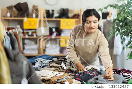 Latin woman choosing sweaters in a clothing store 133012427