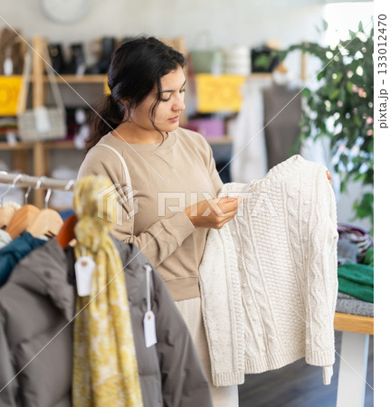 Latin woman choosing sweaters in a clothing store Latin woman choosing sweaters in a clothing store 133012470
