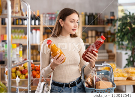Young woman choosing juices in grocery store Young woman choosing juices in grocery store 133012545