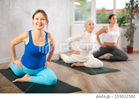 Group of active women practice various yoga poses 133012592