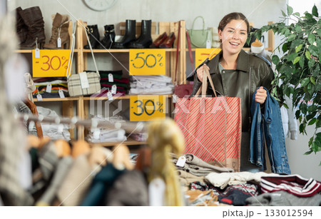 In sales area of store, woman customer chooses trousers 133012594