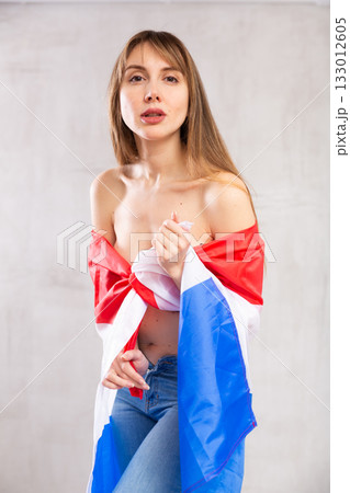 Semi-naked woman wrapped in flag of Netherlands posing in studio 133012605