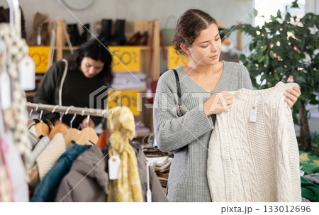 European woman chooses jersey sweater in store 133012696