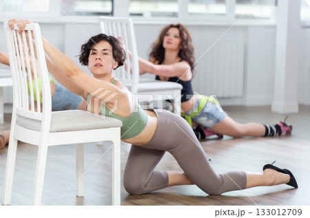 Group of women in high heels rehearsing dance while kneeling on floor 133012709