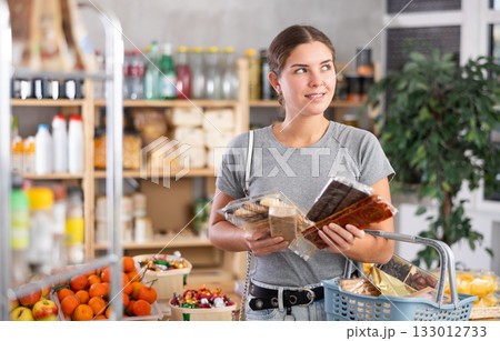 Young woman choosing sweets in grocery store 133012733