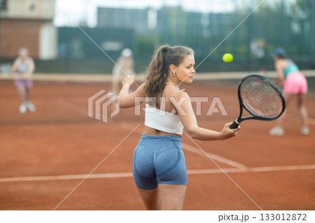 Two young women playing tennis against elderly women Two young women playing tennis against elderly women 133012872