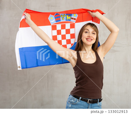 Happy young woman holding flag of Croatia against unicoloured background 133012913