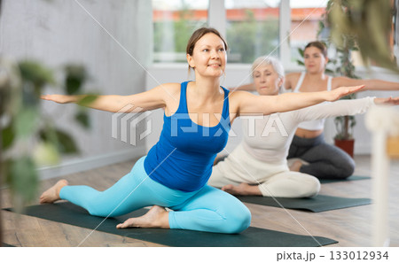 Young woman practicing stretching exercises in yoga studio Young woman practicing stretching exercises in yoga studio 133012934