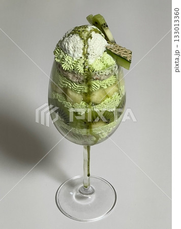 Layered matcha parfait with rich green tea cream, sweet red beans, mochi, and crunchy toppings—offering a perfect balance of earthy bitterness and sweet textures in every delightful spoonful. 133013360