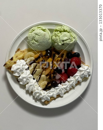 Delicious ice cream-filled crepes, drizzled with chocolate sauce and topped with fresh fruits. Perfect for dessert photography, showcasing the delightful combination of flavors and texture 133013370