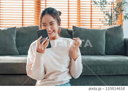 Happy young asian woman relax on comfortable couch at home texting messaging on smartphone Happy young asian woman relax on comfortable couch at home texting messaging on smartphone 133014638