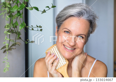 Portrait of a beautiful gray-haired European woman with a wooden comb. Mirror in the bathroom Portrait of a beautiful gray-haired European woman with a wooden comb. Mirror in the bathroom 133014667