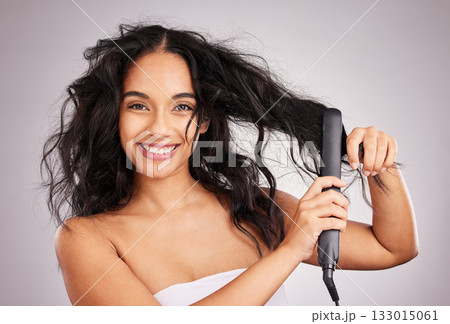 Portrait, happy woman and hair straightener for beauty in studio, treatment and wellness on background. Female model, haircare and heat styling equipment for ironing curly hairstyle, texture or tools 133015061