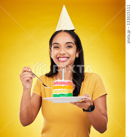 Woman is eating birthday cake, celebration and happy in portrait, rainbow dessert and candle on yellow background. Celebrate, festive and young female, excited for sweet treat and party hat in studio Woman is eating birthday cake, celebration and happy in portrait, rainbow dessert and candle on yellow background. Celebrate, festive and young female, excited for sweet treat and party hat in studio 133015111