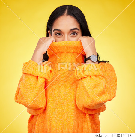 Cold, cover and portrait of a woman with a jersey isolated on a yellow background in a studio. Hiding, winter and a girl holding a jumper up for covering, warmth and bad weather on a backdrop 133015117