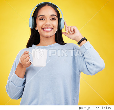 Coffee, music and headphones with portrait of woman in studio for streaming, online radio and relax. Smile, media and podcast with female on yellow background for technology, listening and connection 133015139