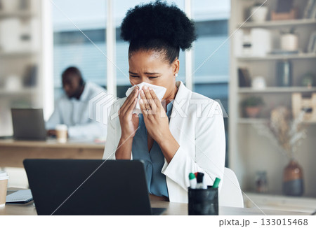 Work, healthcare and black woman at desk blowing nose with tissue paper from flu, cold or hay fever. Sick, exhausted office employee with allergy and sinus problem, health risk from illness at laptop 133015468