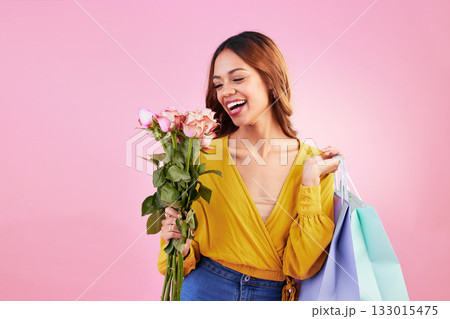 Happy, shopping bags and smile with woman and flowers in studio for retail, birthday and spring. Event, party and celebration with female and roses on pink background for sale, discount and romance 133015475