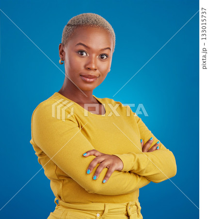 Portrait, fashion and arms crossed with a black woman on a blue background in studio feeling confident. Serious, focus or empowerment and an attractive young female looking proud with confidence Portrait, fashion and arms crossed with a black woman on a blue background in studio feeling confident. Serious, focus or empowerment and an attractive young female looking proud with confidence 133015737