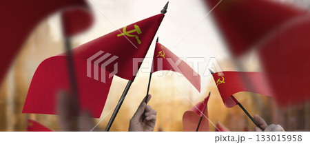 USSR flags in their hands on a blurred urban background USSR flags in their hands on a blurred urban background 133015958
