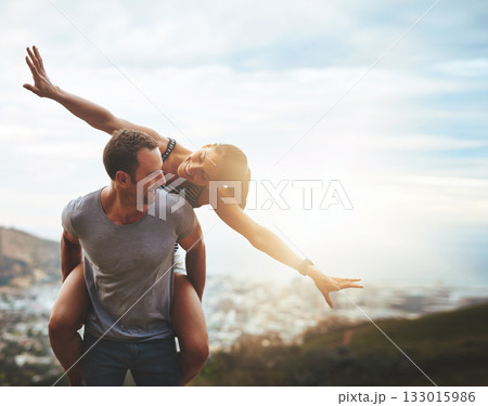 Travel, happy couple with piggyback ride and mountain outdoors with lens flare. Sunshine or mockup space, nature adventure or freedom and people playing on holiday break or summer vacation together. 133015986