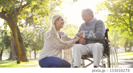 Happy, talking and man in wheelchair with a woman in nature for care and support. Holding hands, smile and an elderly person with a disability and a daughter with love and conversation in a park 133016278