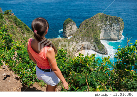 Woman on a cliff and looking on Kelingking beach, Nusa Penida, Indonesia. Woman on a cliff and looking on Kelingking beach, Nusa Penida, Indonesia. 133016396