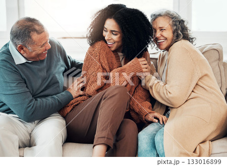 Family, playful and a black woman at her parents home for a visit while bonding on a sofa in the living room together. Love, relax and a senior father tickling his daughter while having fun 133016899
