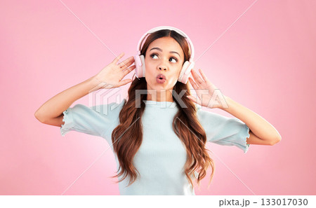 Music headphones, singing and woman whistle in studio isolated on a pink background. Singer, thinking and mixed race female streaming, enjoying and listening to audio, sound track or radio podcast. 133017030