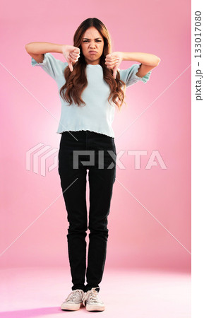 Portrait, sad and thumbs down by hands of woman in studio for bad review, complaint or disappointed on pink background. Face, finger and emoji expression by girl with vote wrong, bad news or reject 133017080