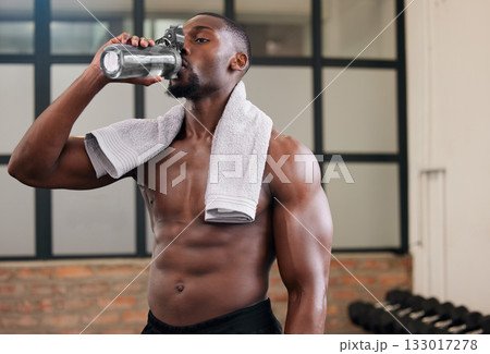 Shirtless black man, gym and water bottle for health, break and energy of workout, training and exercise diet. Thirsty male, abs and drinking for fitness nutrition, body hydration and sports wellness Shirtless black man, gym and water bottle for health, break and energy of workout, training and exercise diet. Thirsty male, abs and drinking for fitness nutrition, body hydration and sports wellness 133017278