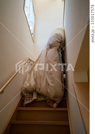 布団を抱えて2階に上がる 133017578