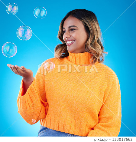 Happy, holding and bubble with indian woman in studio for soap, positive and satisfaction. Magic, creative and smile with female isolated on blue background for bright, cute and entertainment 133017662