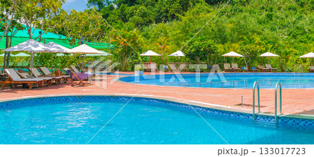 swimming pool at a tropical luxury resort in summer. Tourism and recreation. Landscape panorama with a pool and sun loungers and umbrellas swimming pool at a tropical luxury resort in summer. Tourism and recreation. Landscape panorama with a pool and sun loungers and umbrellas 133017723