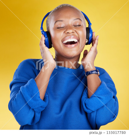 Music, headphones and black woman singing in studio isolated on a yellow background. Podcast, radio singer and happy African female streaming, enjoying and listening to audio, sound track or song. Music, headphones and black woman singing in studio isolated on a yellow background. Podcast, radio singer and happy African female streaming, enjoying and listening to audio, sound track or song. 133017780