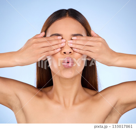 Beauty, skincare and woman cover eyes, dermatology and treatment against a blue studio background. Female, cosmetics and lady hands on face, morning routine and grooming with surprise and soft skin Beauty, skincare and woman cover eyes, dermatology and treatment against a blue studio background. Female, cosmetics and lady hands on face, morning routine and grooming with surprise and soft skin 133017861